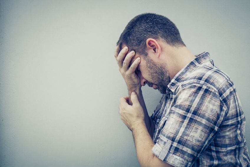 44059129 - portrait one sad man standing near a wall and covers his face at the day